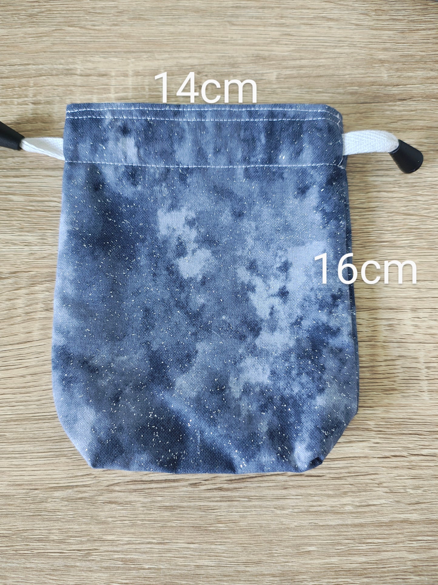 Grey drawstring bag with measurements on a wooden surface