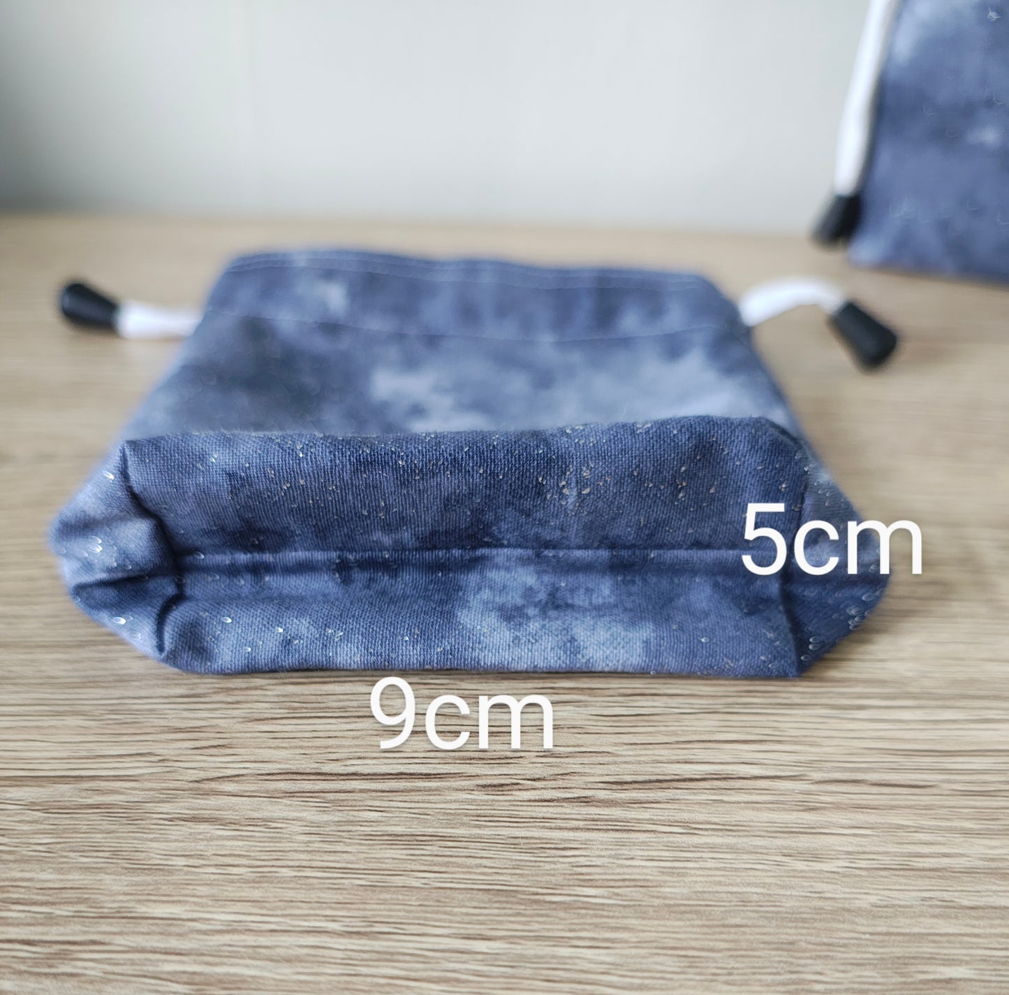 G fabric drawstring bag with measurements on a wooden surfaceey