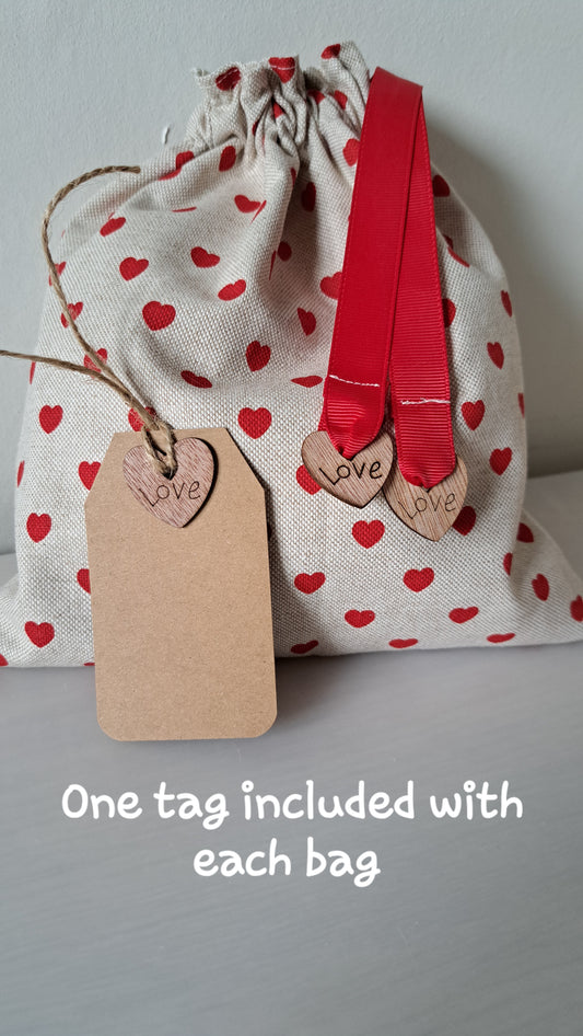 Drawstring bag with red heart pattern, red ribbons, and a 'love' tag on a gray background.