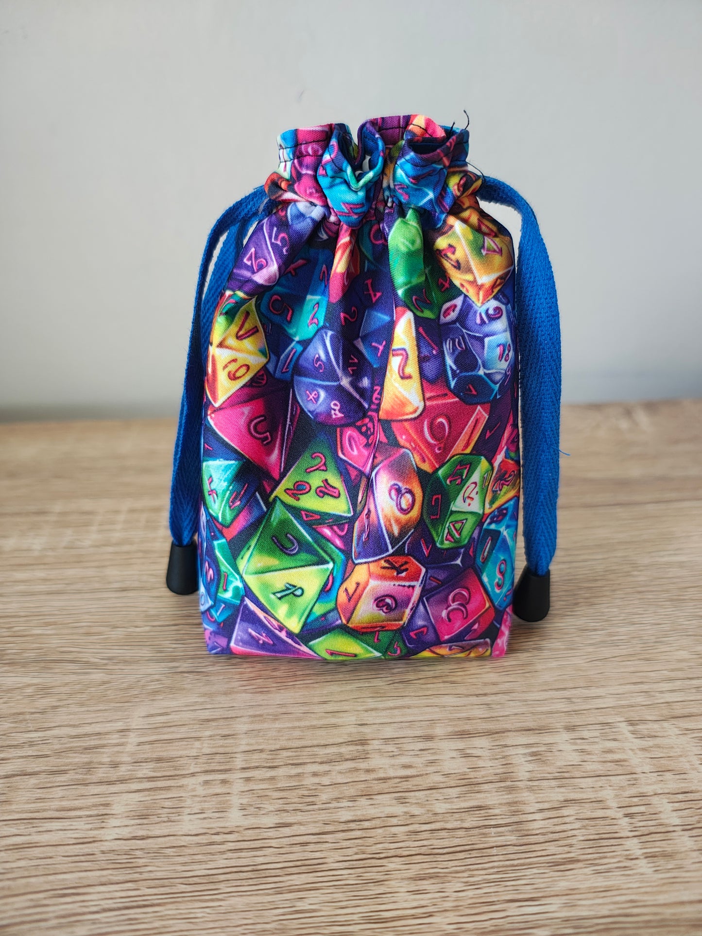Colorful dice set in a drawstring bag on a wooden surface