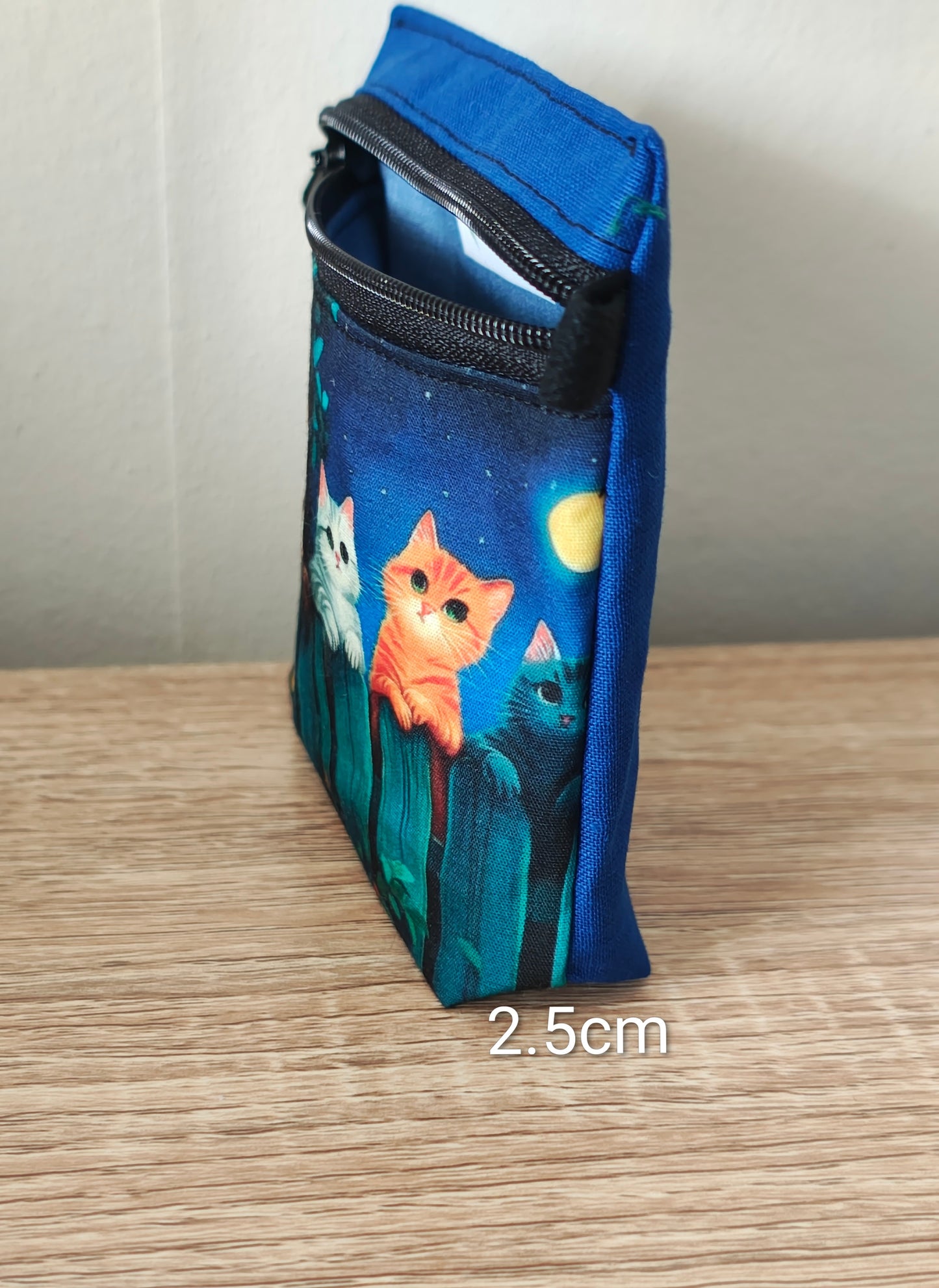 Blue pouch with cat illustrations on a wooden surface