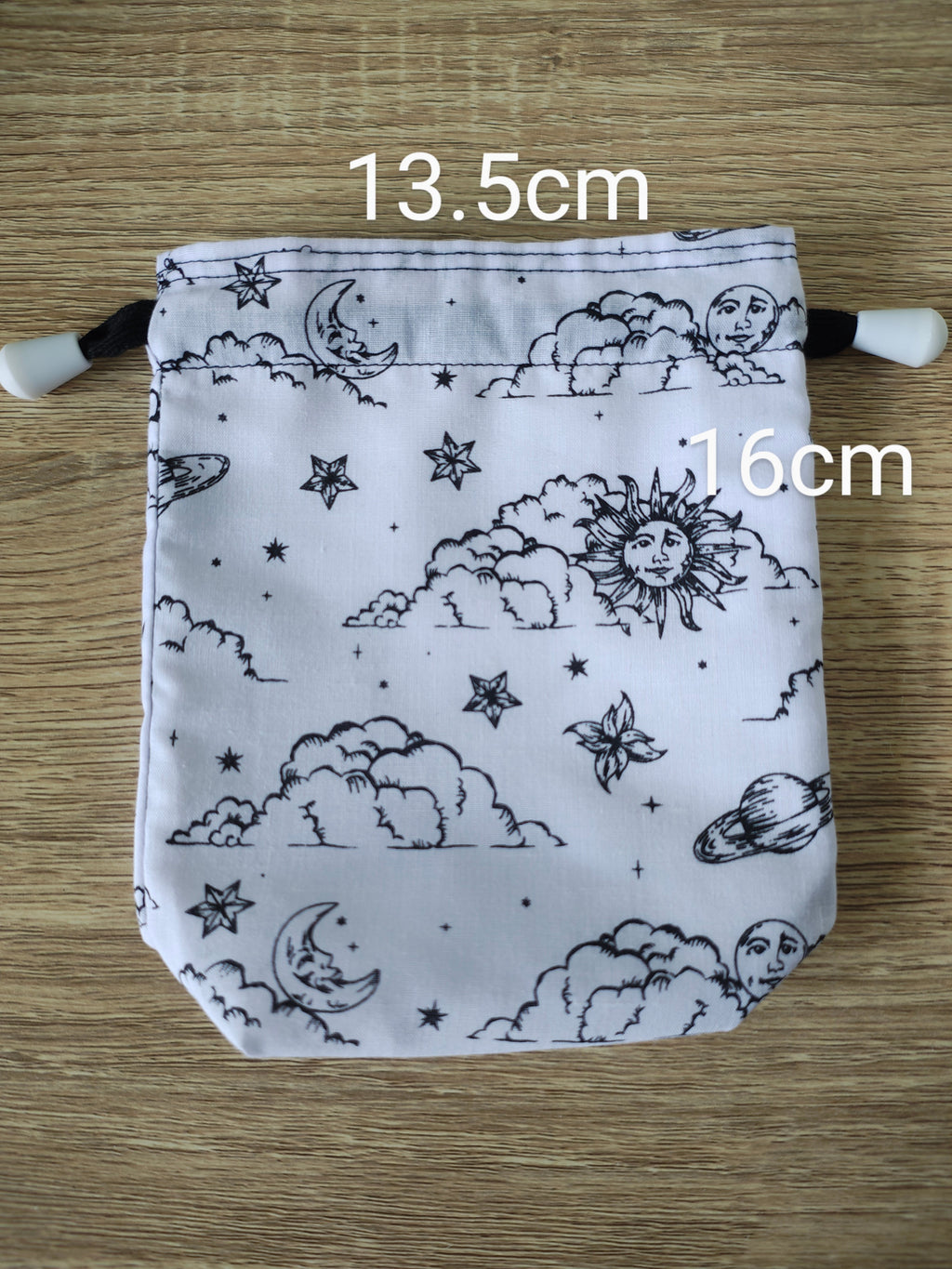 Drawstring bag with celestial pattern on a wooden surface, showing measurements.