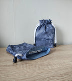 Two grey drawstring bags on a wooden surface with a neutral background