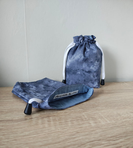 Two grey drawstring bags on a wooden surface with a neutral background