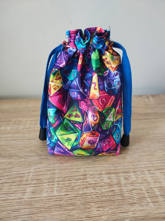 Colorful dice set in a drawstring bag on a wooden surface