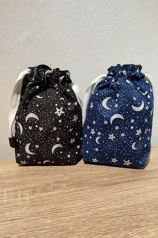 Two drawstring bags with star and moon patterns on a wooden surface.